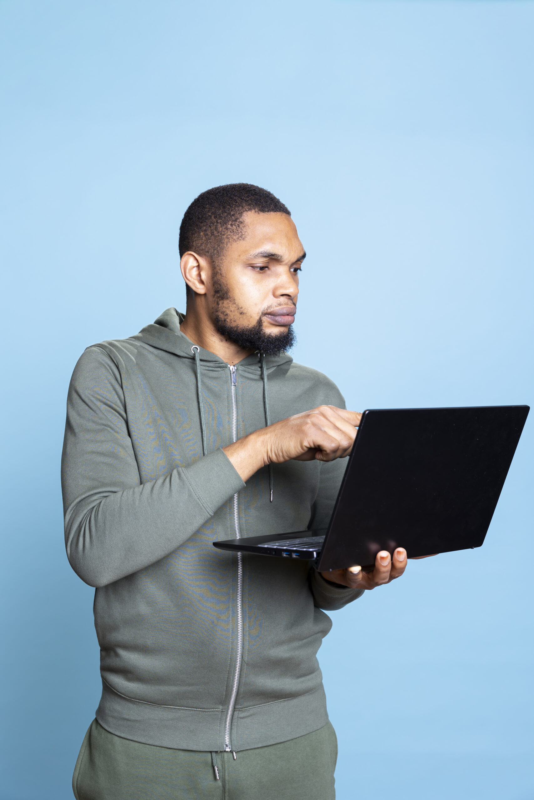 Carefree happy african american guy working on his laptop in studio